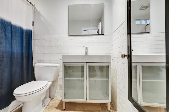 bathroom with tile patterned flooring, vanity, tile walls, and toilet