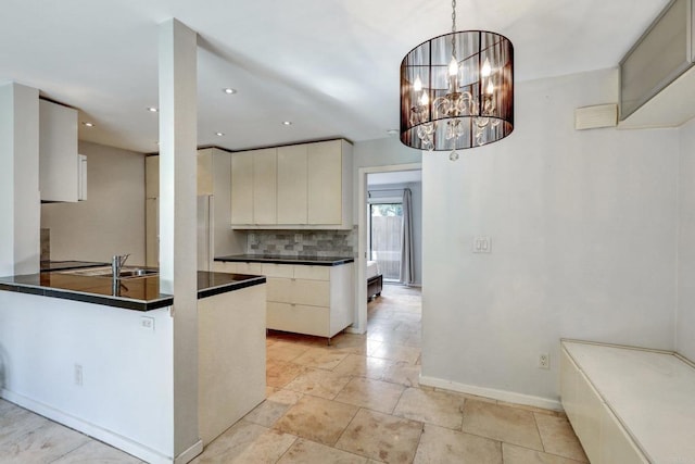 kitchen featuring sink, hanging light fixtures, an inviting chandelier, kitchen peninsula, and decorative backsplash