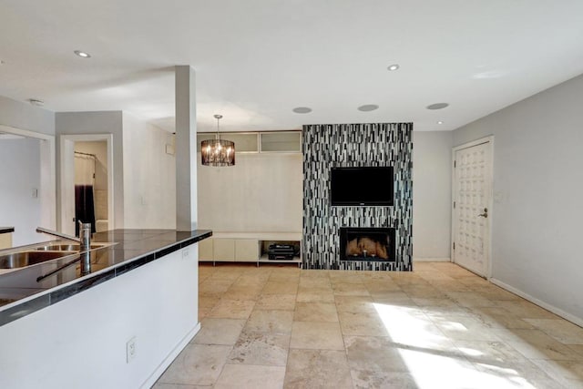 kitchen featuring decorative light fixtures, sink, a fireplace, and a chandelier