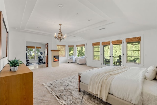 carpeted bedroom featuring french doors, access to outside, a tray ceiling, and a notable chandelier