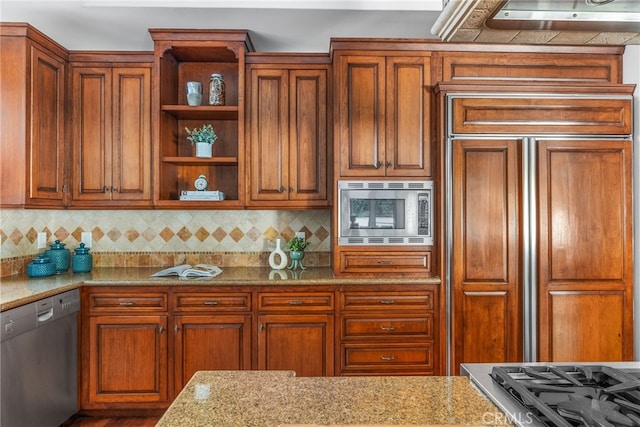 kitchen featuring light stone countertops, built in appliances, and backsplash