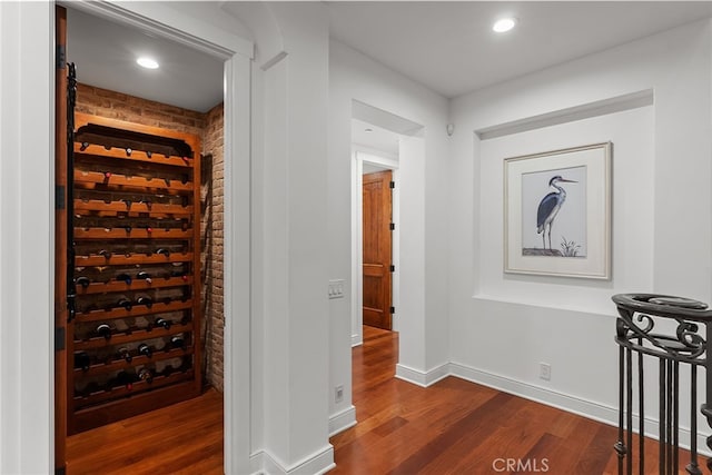 wine cellar with dark wood-type flooring and brick wall