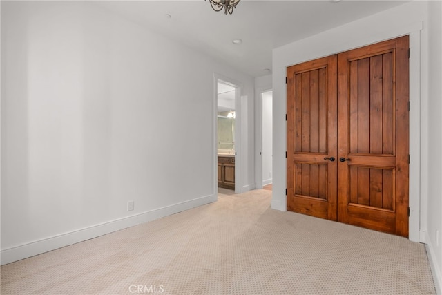 unfurnished bedroom featuring light colored carpet and connected bathroom