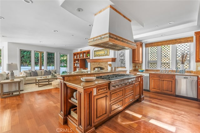 kitchen featuring custom range hood, stainless steel appliances, sink, light hardwood / wood-style flooring, and a kitchen island