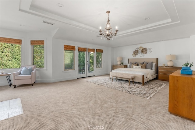 bedroom featuring a raised ceiling, multiple windows, a chandelier, and access to outside