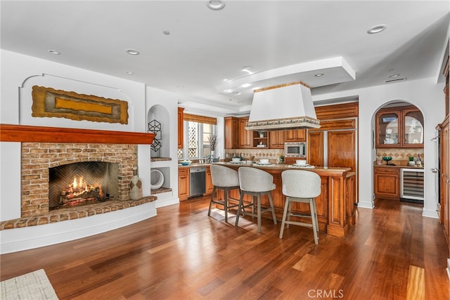 kitchen featuring a kitchen breakfast bar, wine cooler, dark hardwood / wood-style floors, a kitchen island, and stainless steel appliances