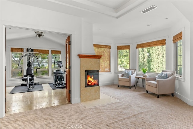 sitting room featuring light carpet, lofted ceiling, a tile fireplace, and a healthy amount of sunlight