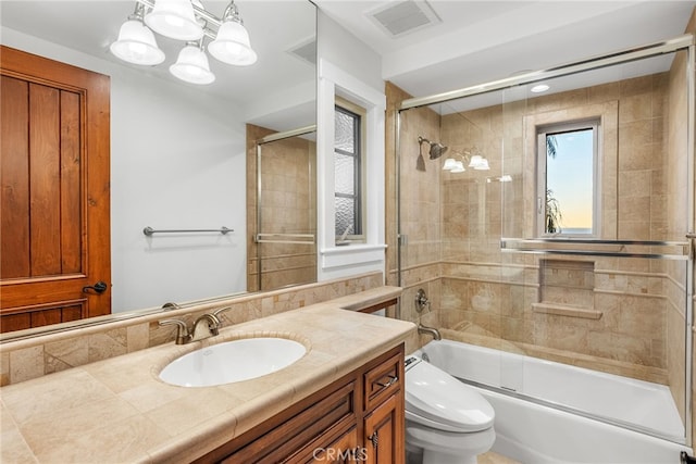 full bathroom featuring an inviting chandelier, vanity, bath / shower combo with glass door, and toilet