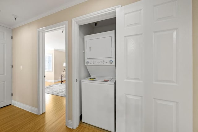 clothes washing area with stacked washer and clothes dryer, ornamental molding, and light hardwood / wood-style floors