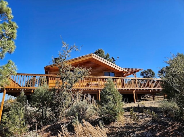 back of house with log veneer siding and a wooden deck