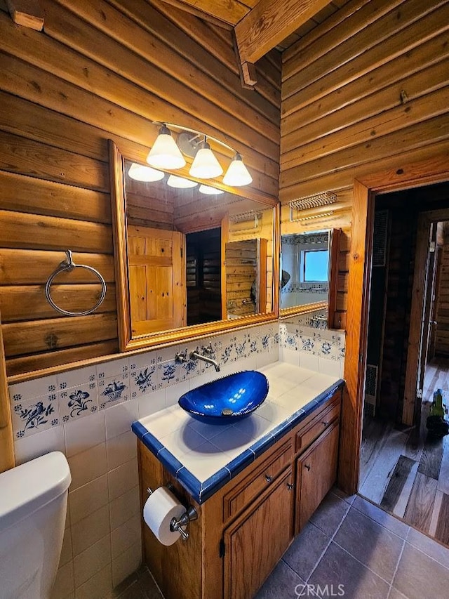 bathroom featuring tile patterned floors, vanity, toilet, and tile walls