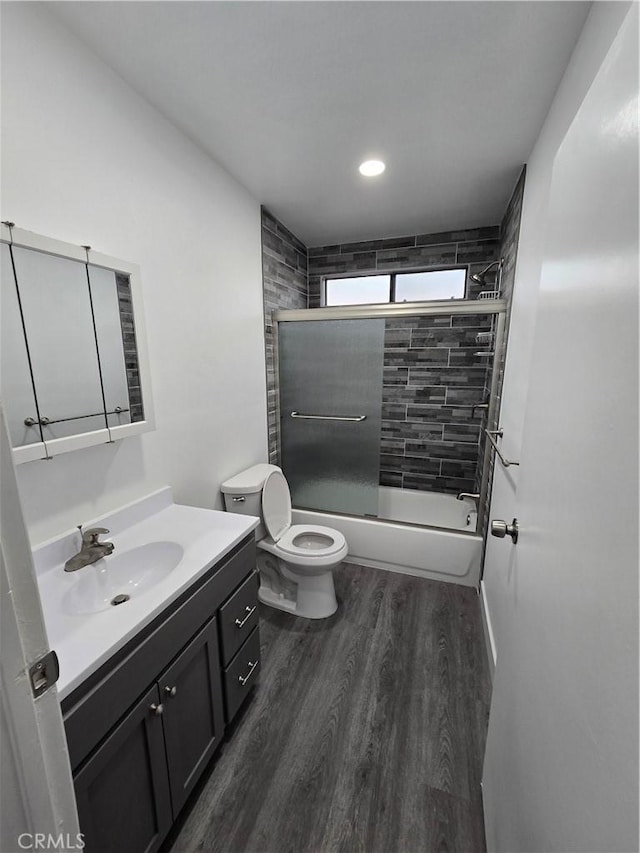 full bathroom with shower / bath combination with glass door, wood-type flooring, vanity, and toilet