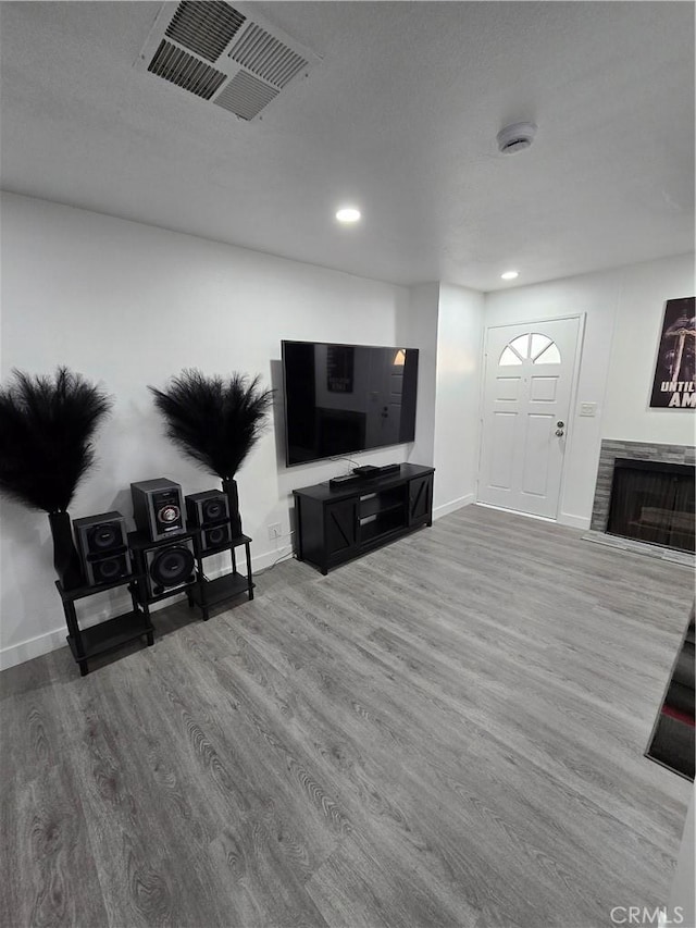 living room featuring a stone fireplace and hardwood / wood-style floors