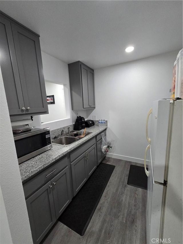 kitchen featuring light stone countertops, gray cabinetry, dark wood-type flooring, sink, and white refrigerator