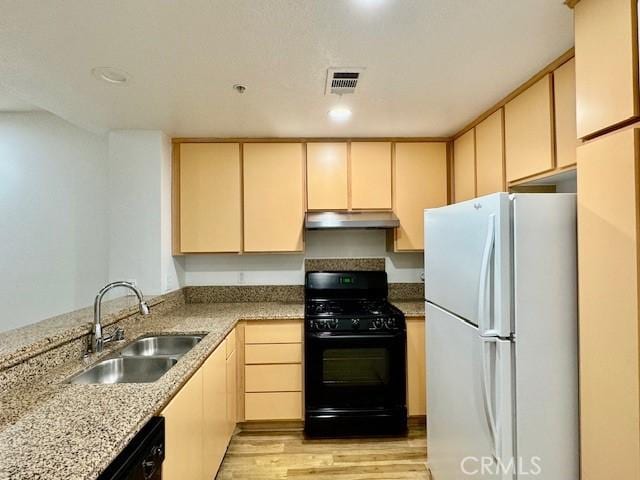 kitchen featuring white fridge, light hardwood / wood-style floors, black gas range oven, and light brown cabinets