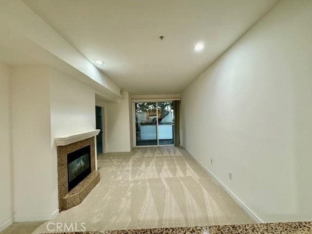 unfurnished living room featuring light colored carpet and a premium fireplace