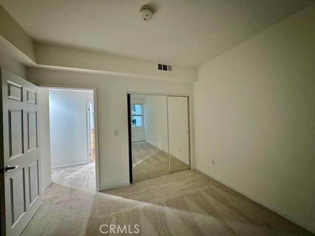 unfurnished bedroom featuring light carpet and a closet