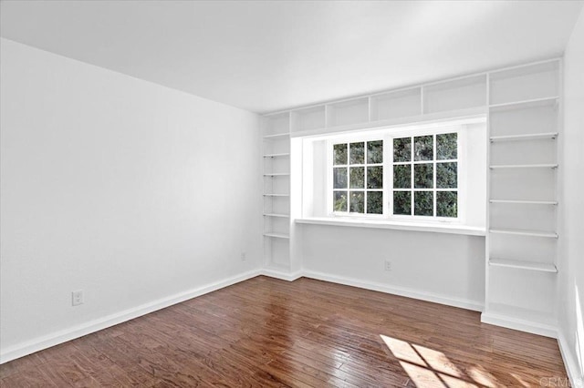 empty room featuring dark wood-style floors and baseboards