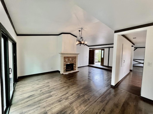 unfurnished living room with a fireplace with raised hearth, wood finished floors, baseboards, an inviting chandelier, and crown molding