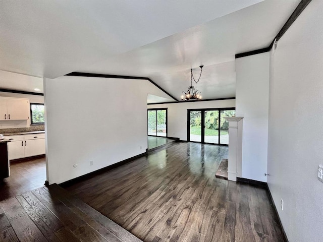 unfurnished living room featuring a notable chandelier, dark wood finished floors, and baseboards