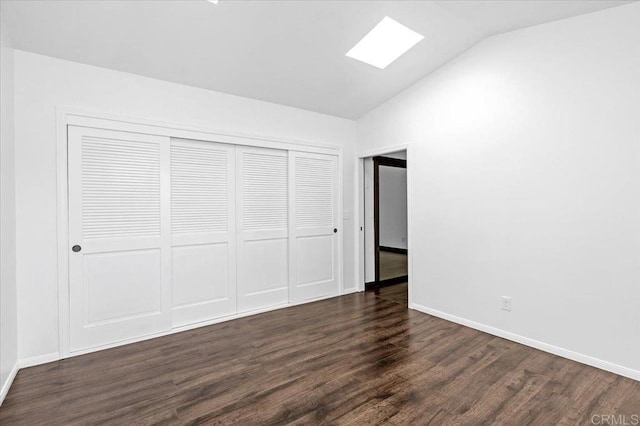 unfurnished bedroom with vaulted ceiling with skylight, baseboards, dark wood finished floors, and a closet