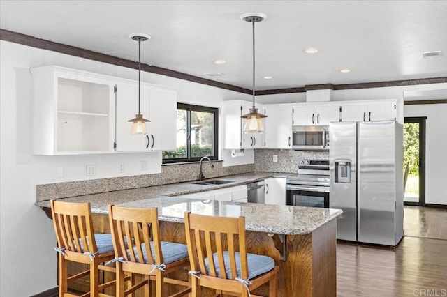 kitchen with appliances with stainless steel finishes, pendant lighting, white cabinets, and a breakfast bar area