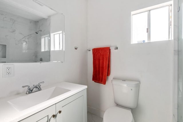 bathroom with tiled shower, vanity, and toilet