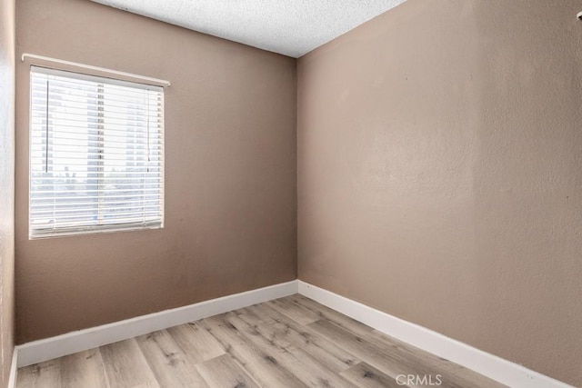 spare room with light hardwood / wood-style flooring and a textured ceiling