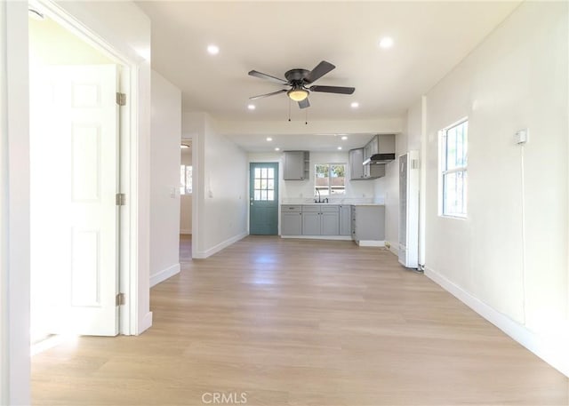 interior space with ceiling fan, sink, and light wood-type flooring