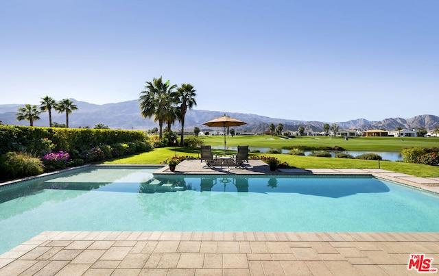 view of swimming pool with a yard, a water and mountain view, and a patio