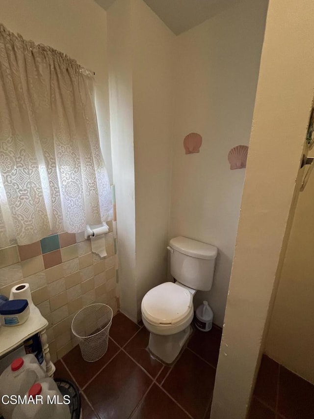 bathroom with tile patterned flooring, toilet, and tile walls