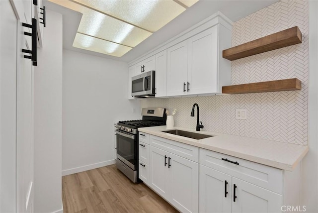 kitchen with sink, white cabinets, stainless steel appliances, and light hardwood / wood-style floors