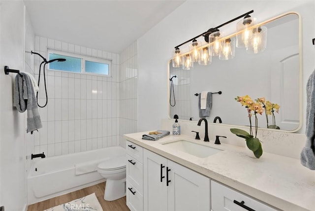 full bathroom with hardwood / wood-style floors, vanity, tiled shower / bath combo, and toilet