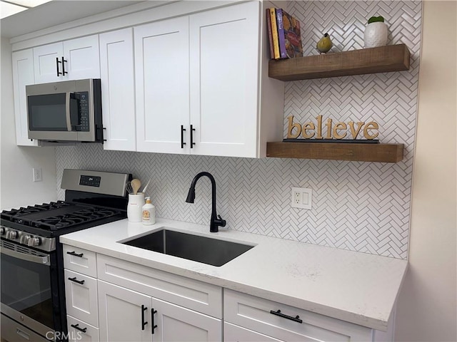 kitchen featuring tasteful backsplash, open shelves, appliances with stainless steel finishes, white cabinetry, and a sink