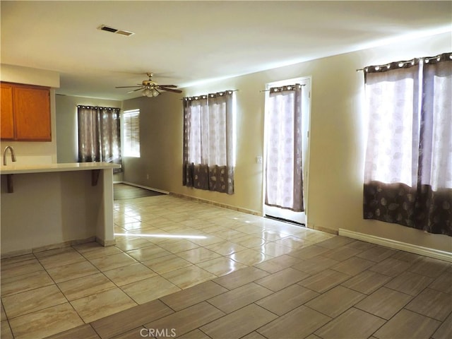 interior space with a breakfast bar, light tile patterned floors, and ceiling fan