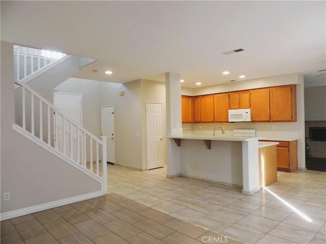 kitchen featuring kitchen peninsula, range, a kitchen bar, and sink