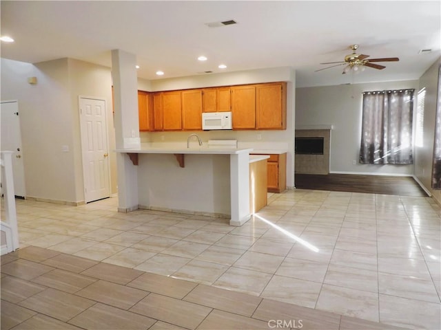 kitchen featuring a kitchen bar, kitchen peninsula, ceiling fan, and sink