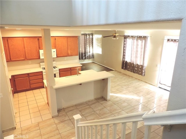 kitchen featuring a kitchen bar, white appliances, ceiling fan, and light tile patterned flooring