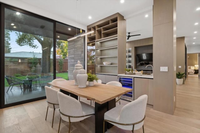 dining room featuring ceiling fan, sink, beverage cooler, and light wood-type flooring