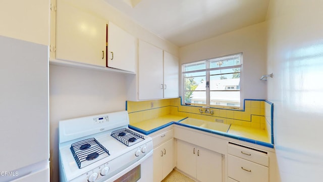 kitchen with white range oven, white cabinetry, tasteful backsplash, and sink