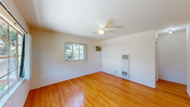 unfurnished room with a wall mounted air conditioner, ceiling fan, and wood-type flooring