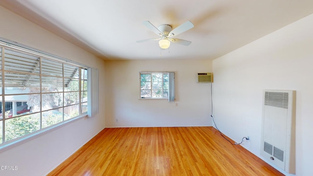 empty room with a wall mounted air conditioner, wood-type flooring, and a wealth of natural light