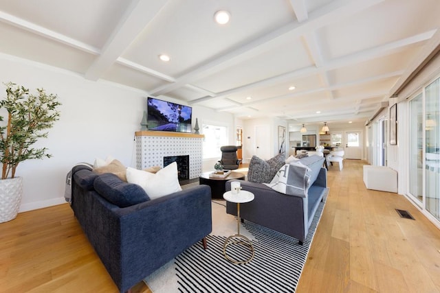 living room featuring a fireplace, beam ceiling, light hardwood / wood-style floors, and coffered ceiling