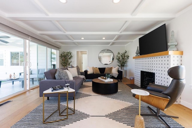 living room featuring coffered ceiling, beam ceiling, wood-type flooring, and a tiled fireplace