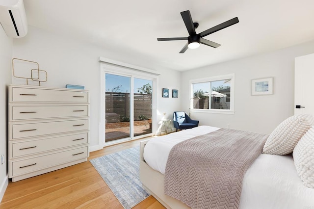 bedroom with an AC wall unit, access to exterior, ceiling fan, and light wood-type flooring