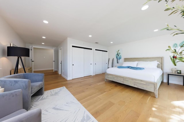 bedroom with light hardwood / wood-style flooring and multiple closets