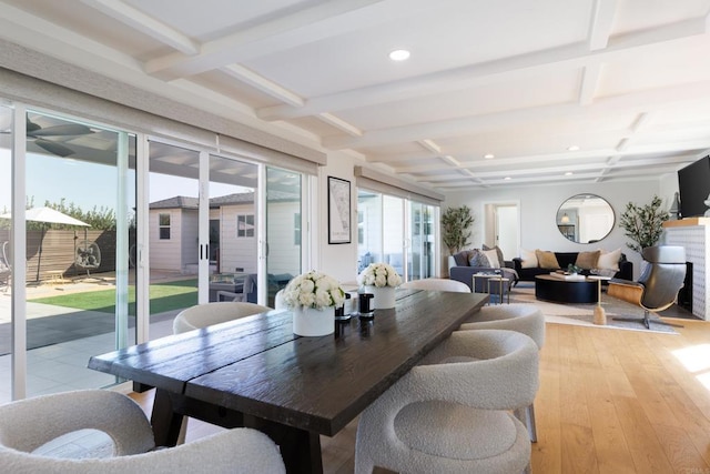 dining space with light hardwood / wood-style flooring, beamed ceiling, and coffered ceiling