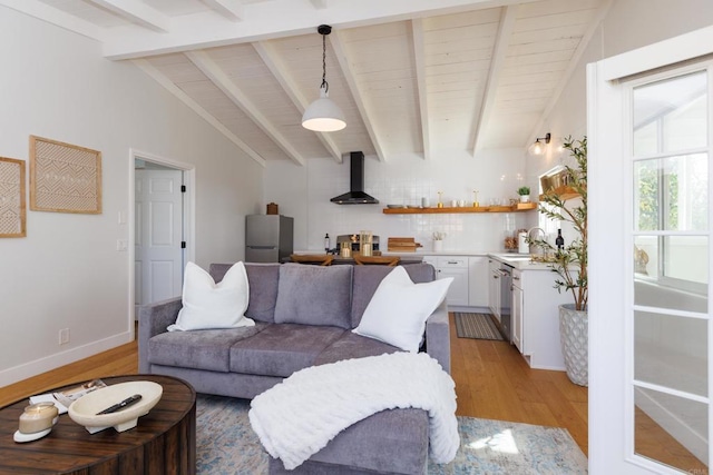 living room with vaulted ceiling with beams, sink, and light hardwood / wood-style floors