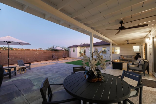 patio terrace at dusk featuring outdoor lounge area, ceiling fan, and an outdoor structure