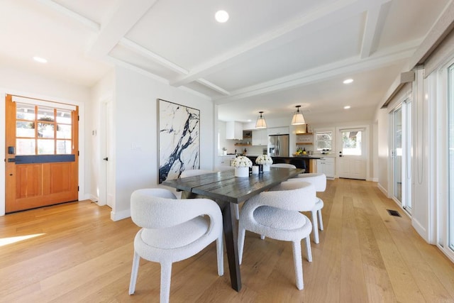 dining space featuring beam ceiling and light hardwood / wood-style flooring